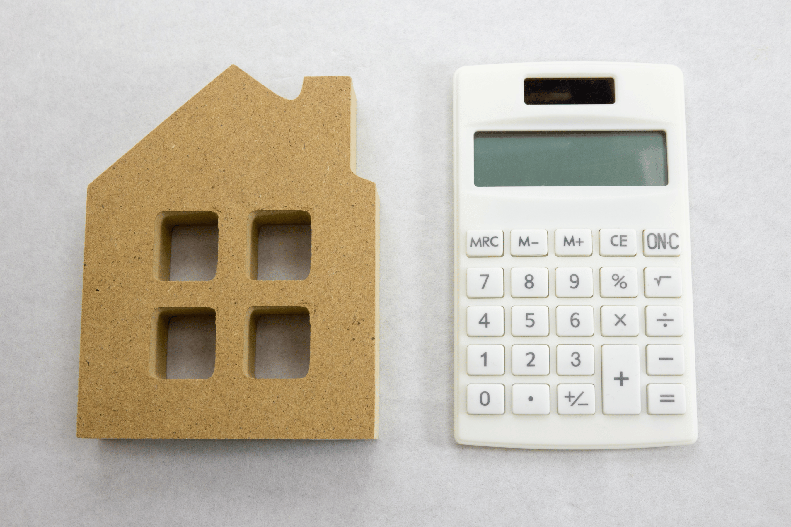 Cardboard cutout of a house beside a calculator
