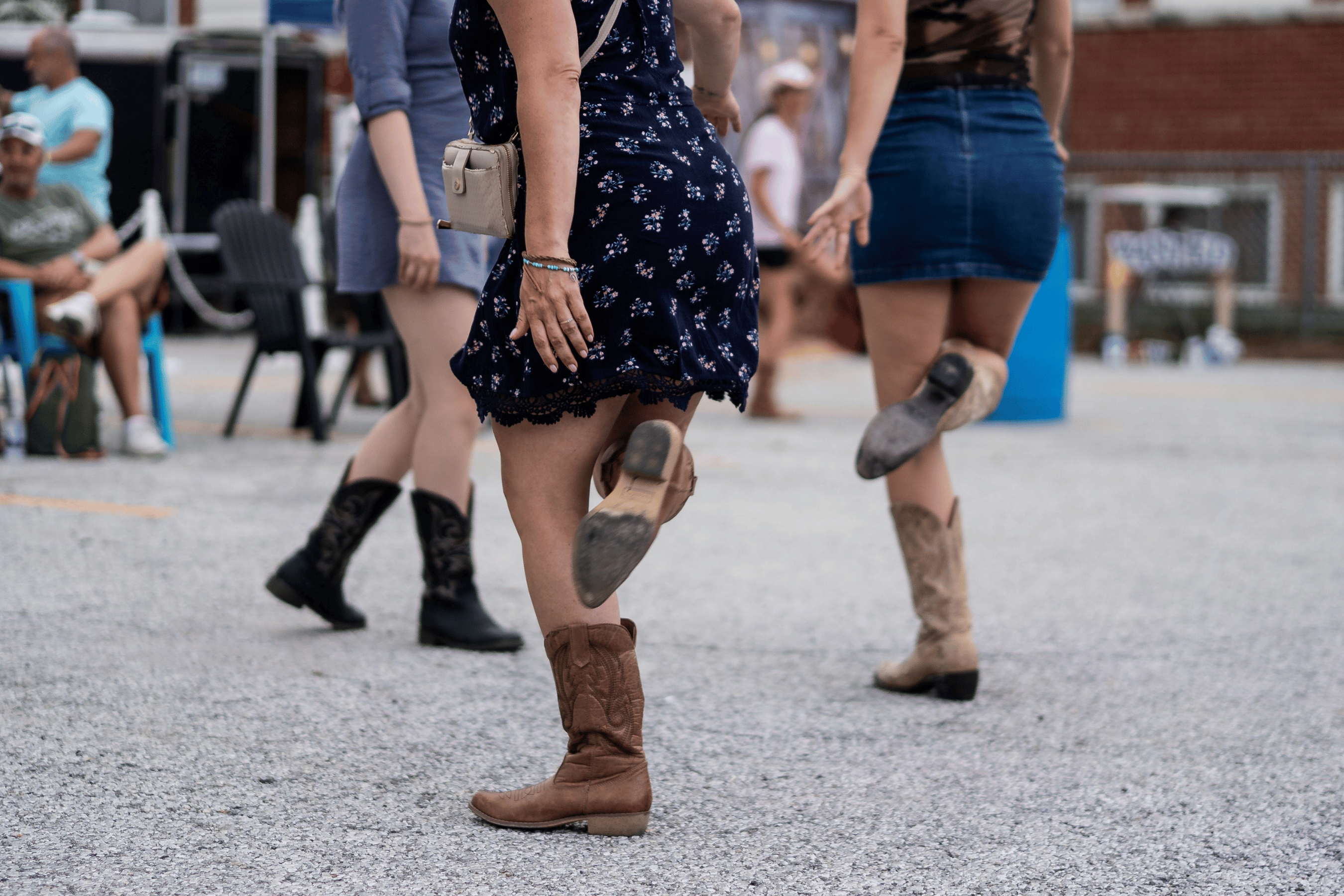 Women dance in cowgirl boots on the pavement