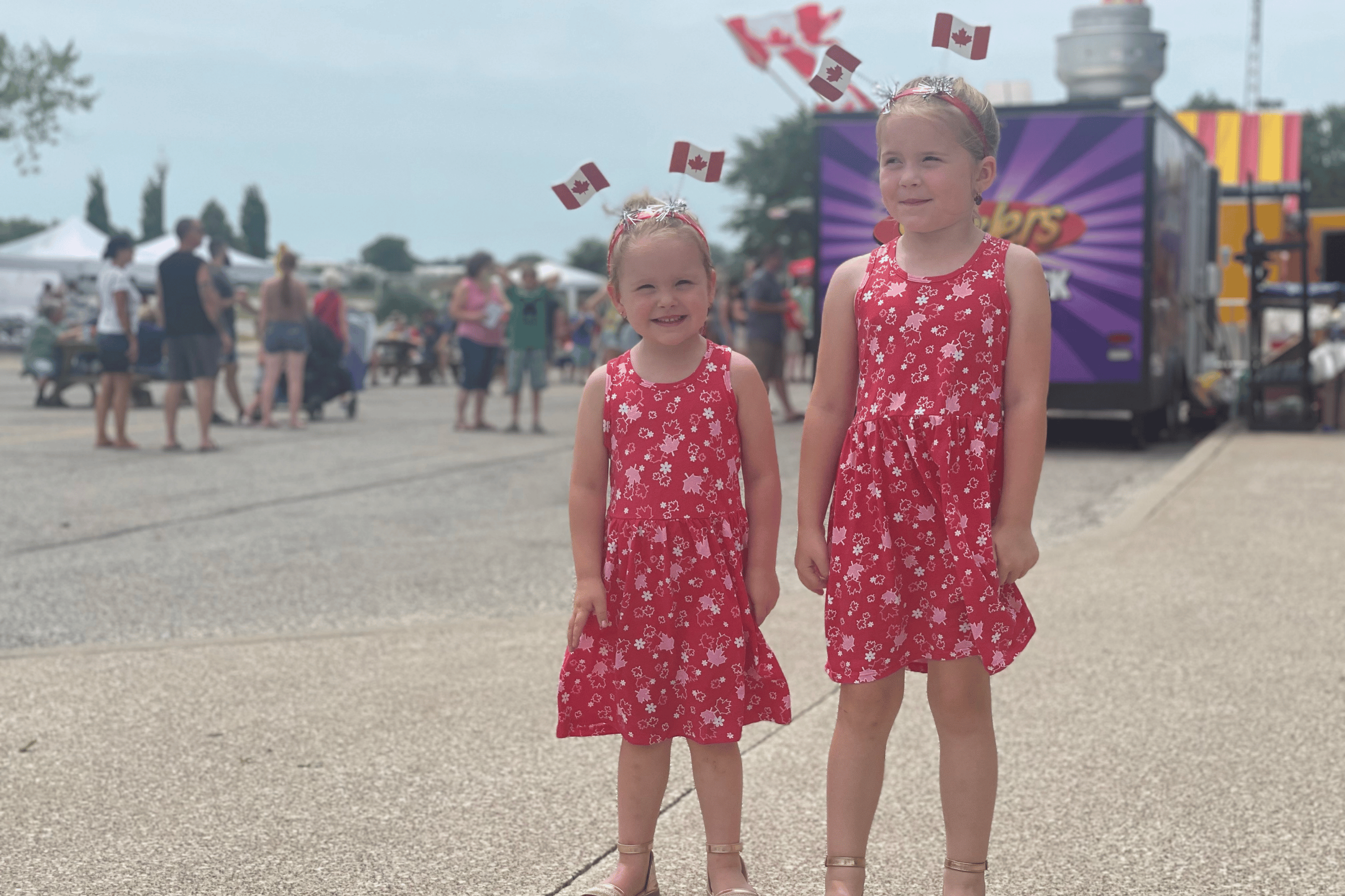 Two young girls in matching Canada Day dresses with flags in their hair