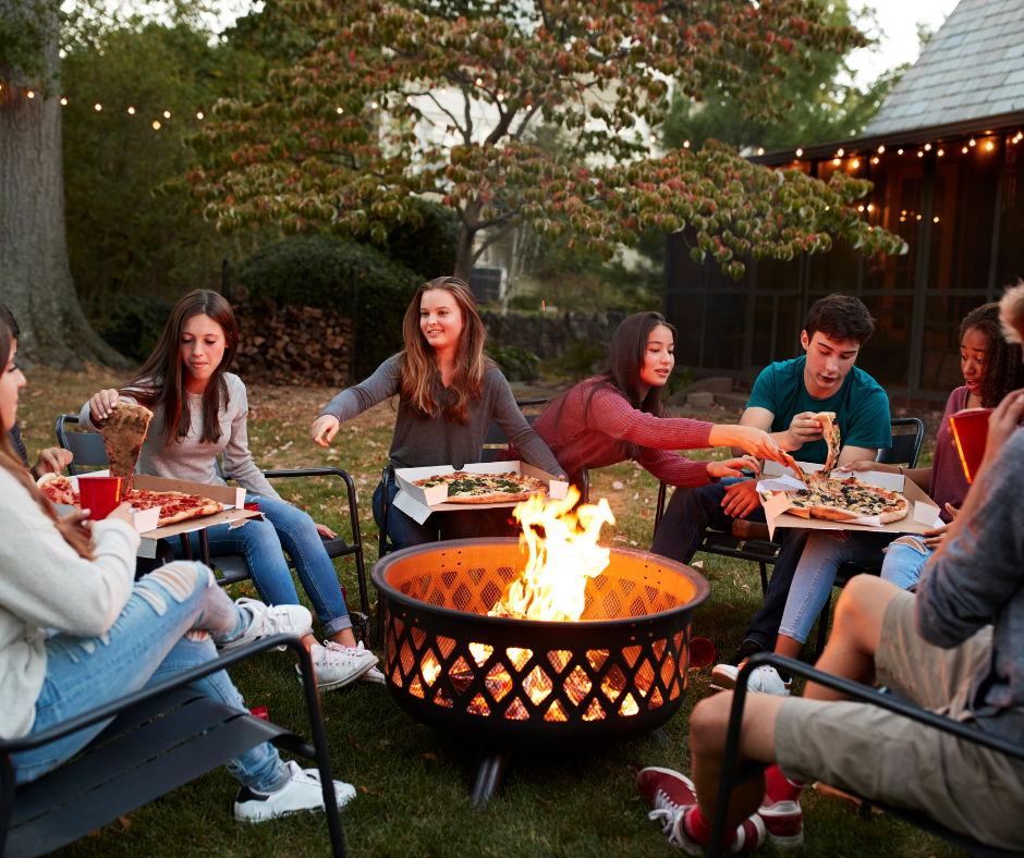 Friends gather around a backyard firepit