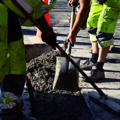 Construction workers use equipment close to a road 
