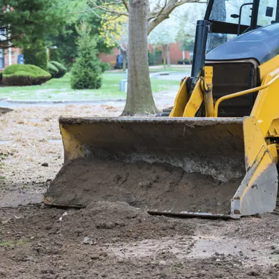 Yellow scraper moves dirt on property