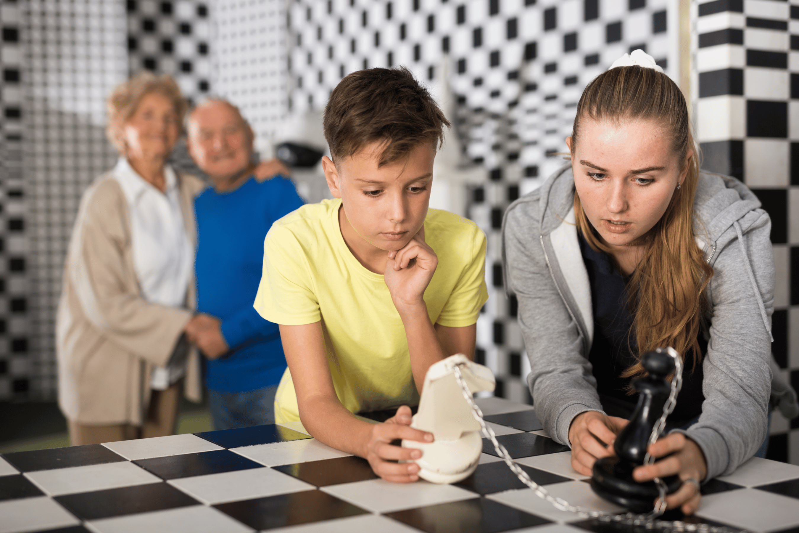 Kids complete a chess puzzle while their grandparents smile behind them