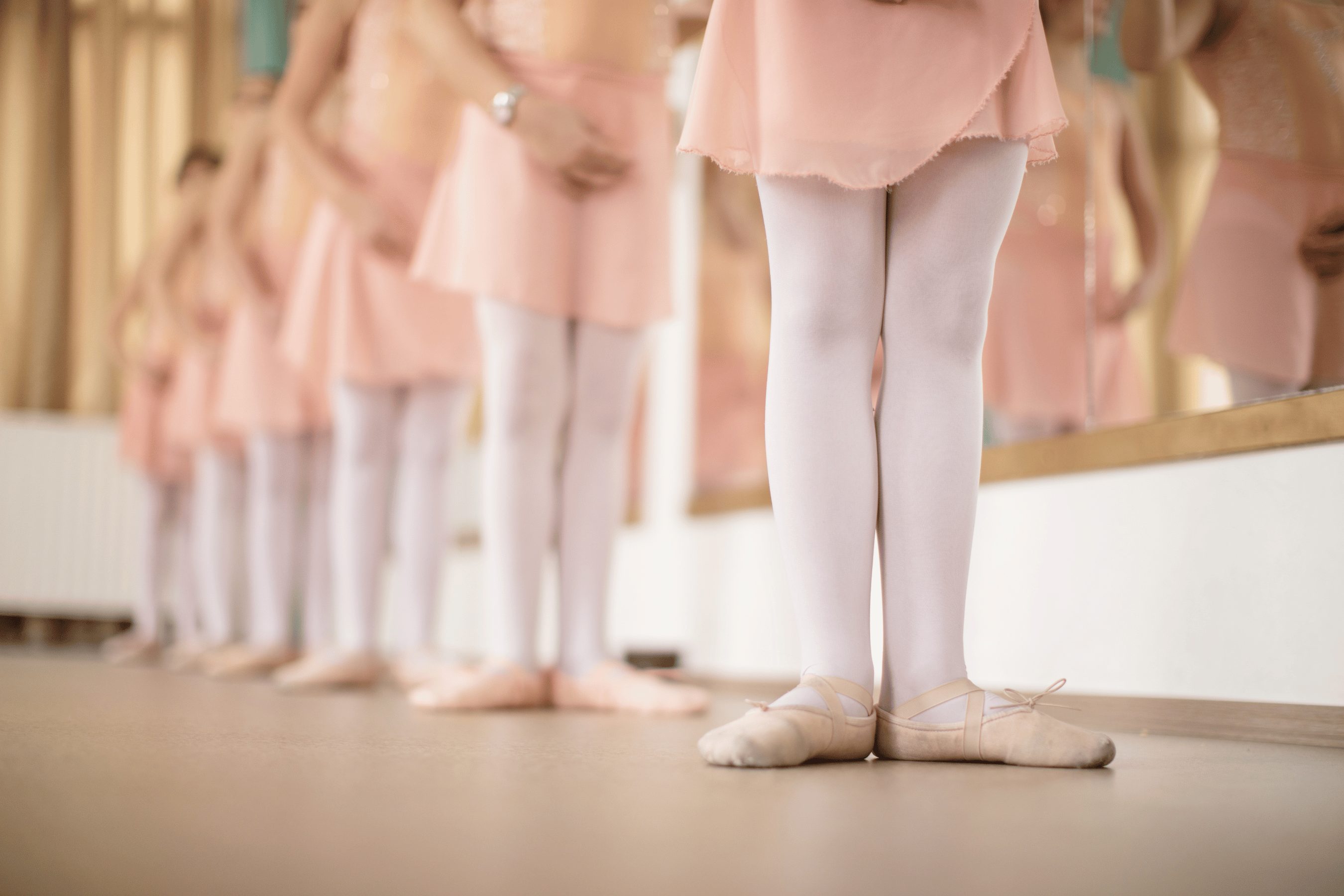Row of ballet dancer legs in front of a mirror
