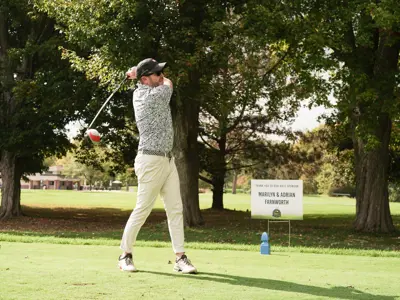 A golfer swings his club on the green