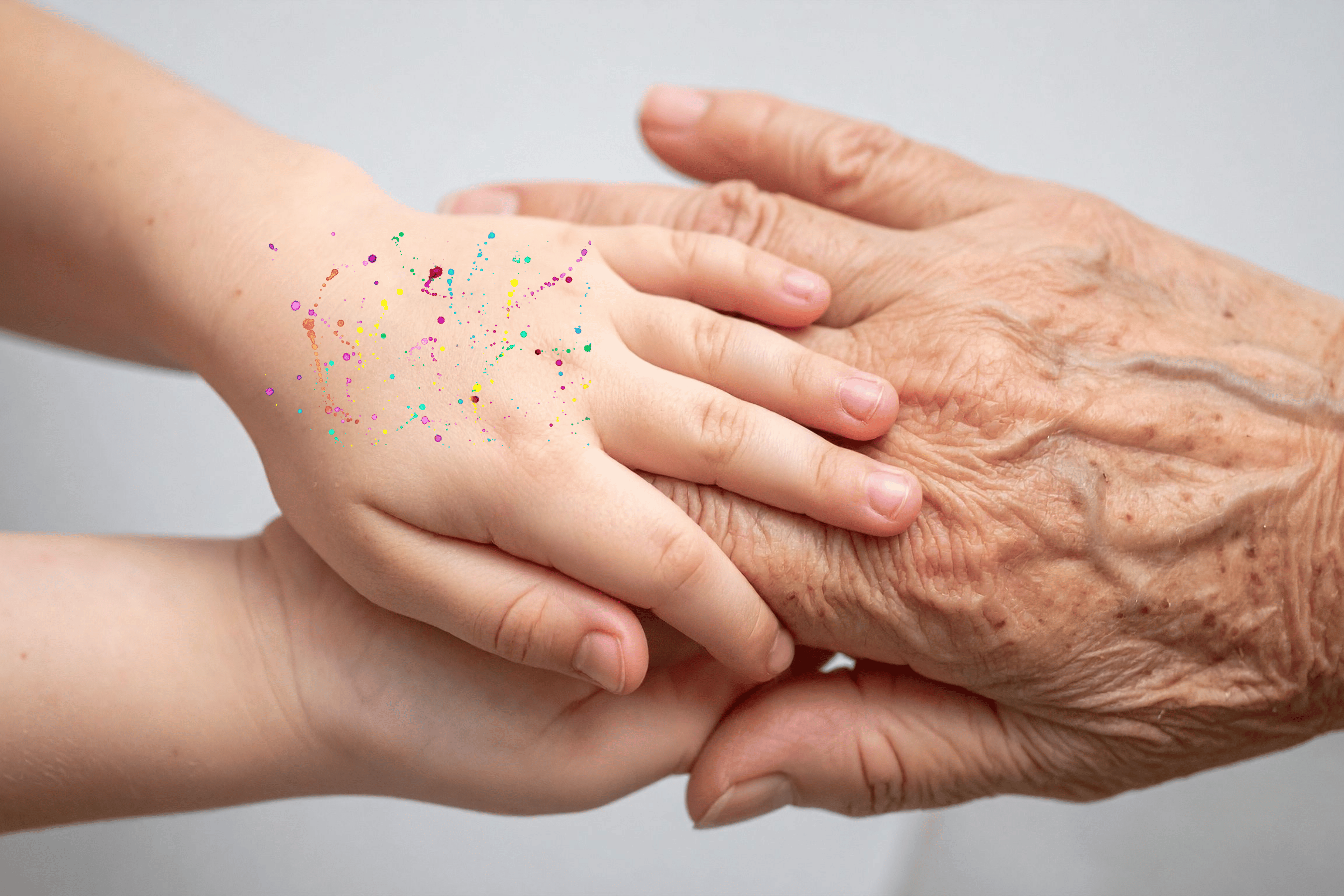 Young paint speckled hands hold a mature hand