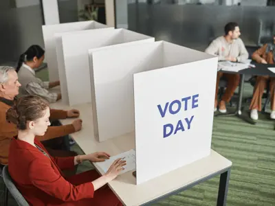 People vote at ballot boxes that say "Vote Day"