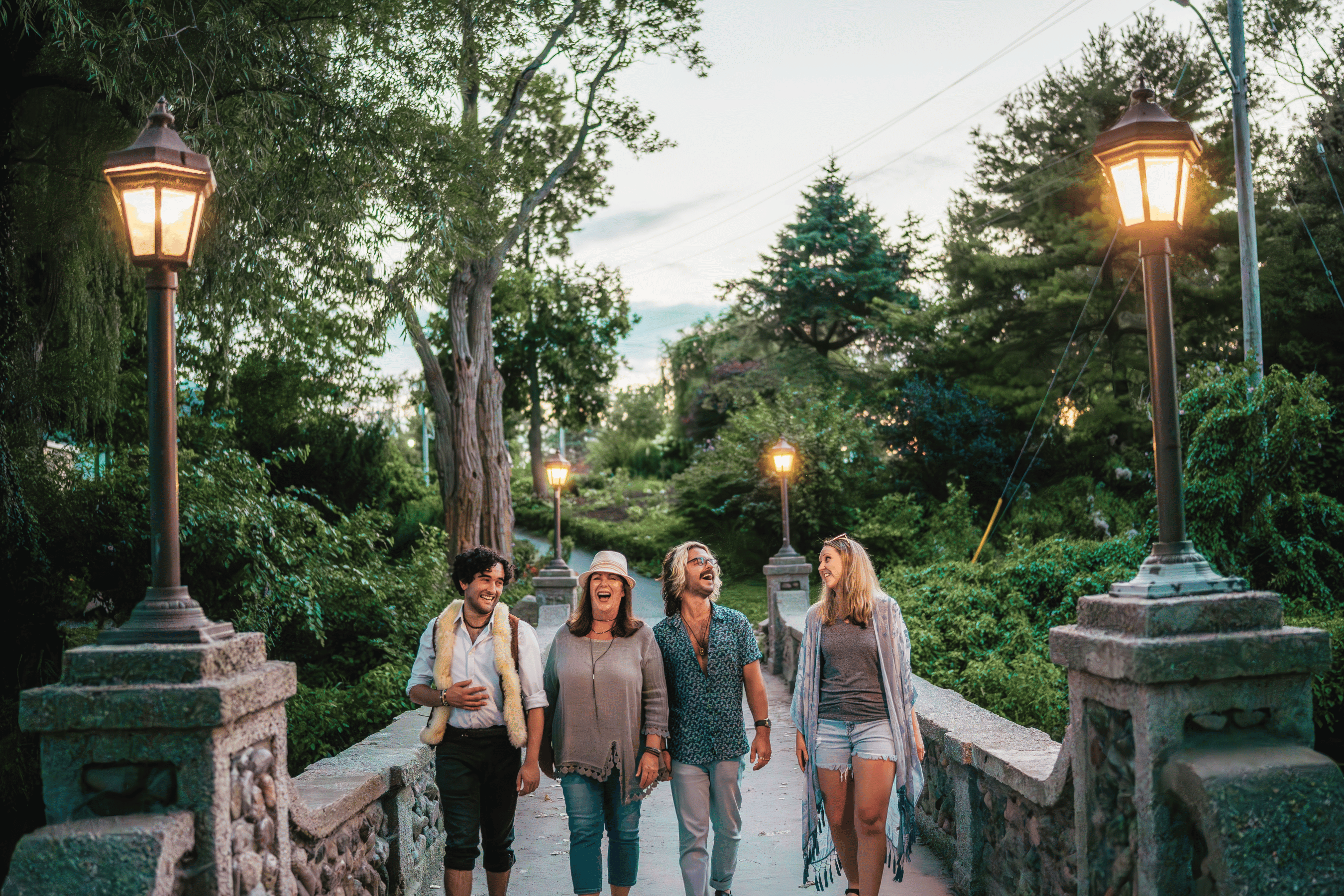 A group of young adults walk across a lit up stone heritage bridge