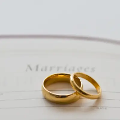 Two gold rings sit on top of a marriage certificate